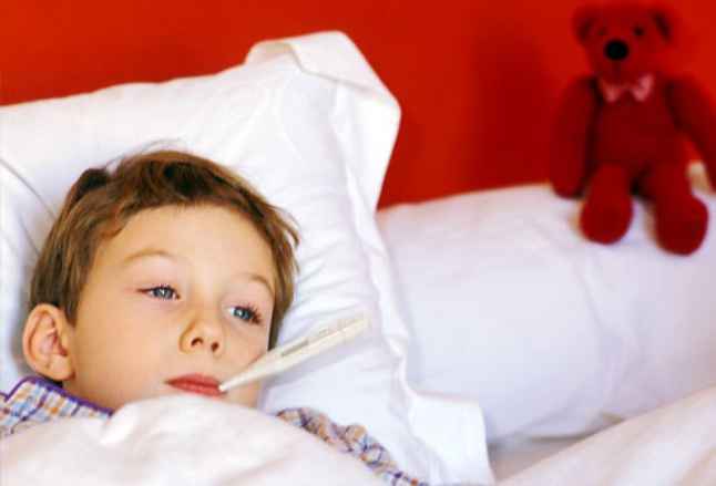 ребёнок  с  термометром  во  рту  лежит  в  кровати